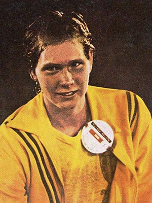 Color photograph of Olympic swimmer Melissa Belote. It is a head-and-shoulders portrait. She is wearing a yellow jacket over a yellow t-shirt.